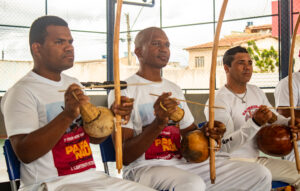 Mestres capoeiristas tocando berimbaus.